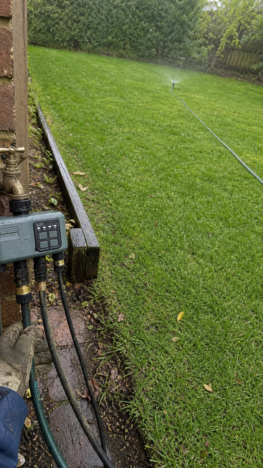 Johgee water timer in a rainy lawn sprinkler garden scene